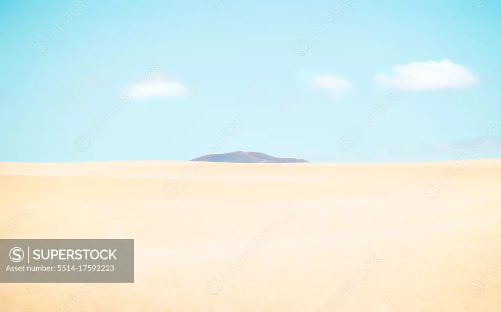 Desert landscape with a mountain between the dunes on sunny day.