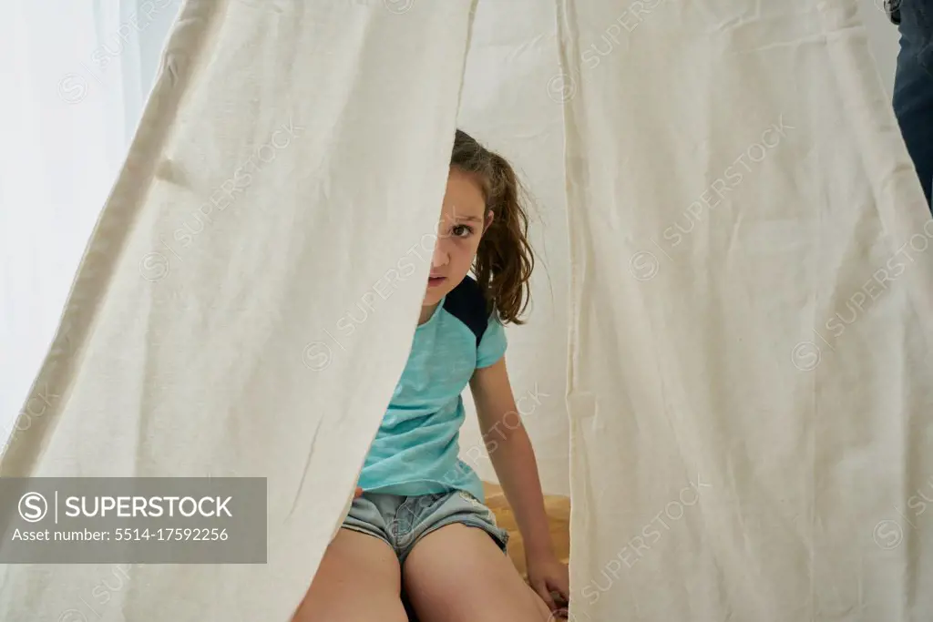 girl looking in a white teepee tent inside their house. home concept