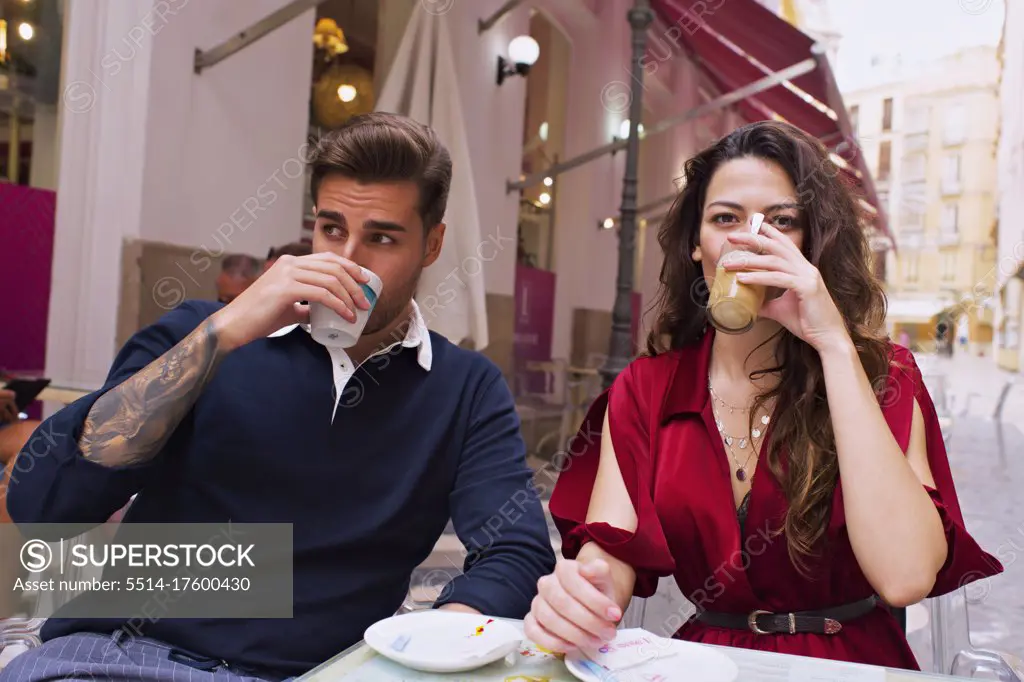 Young couple drink coffee on the terrace of a bar