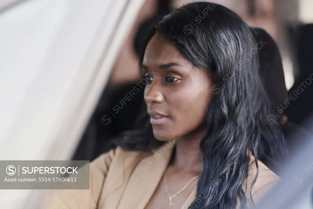 Portrait of black woman wearing a brown suit driving a car. business concept