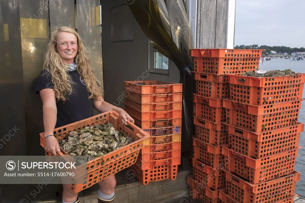 Female shellfish farmer holding crate of oysters