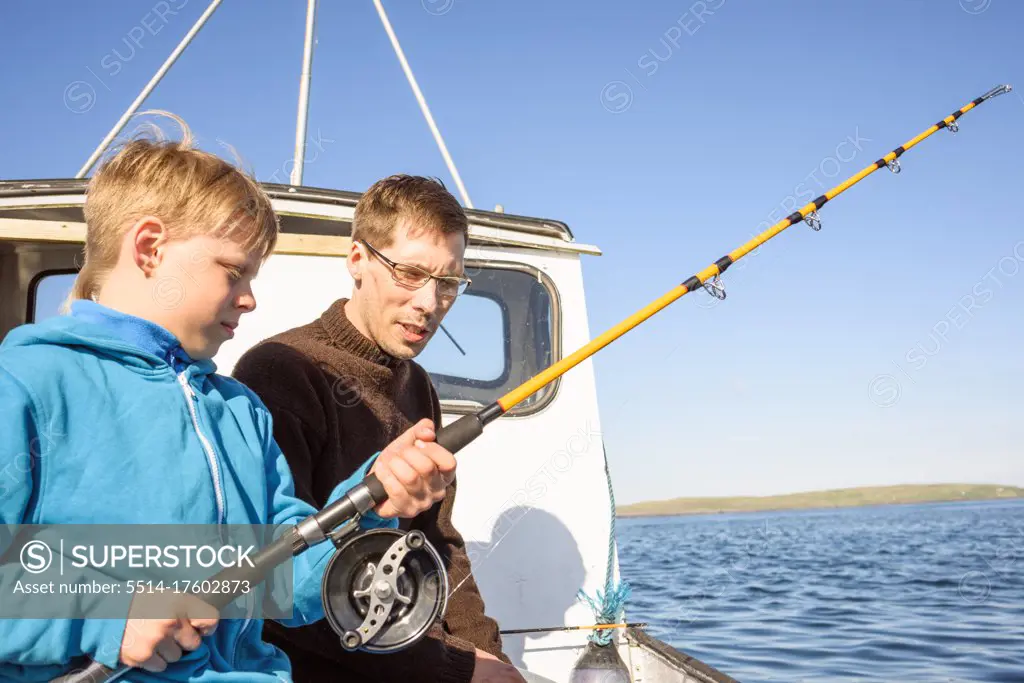 Male fisher teaching boy fishing on boat