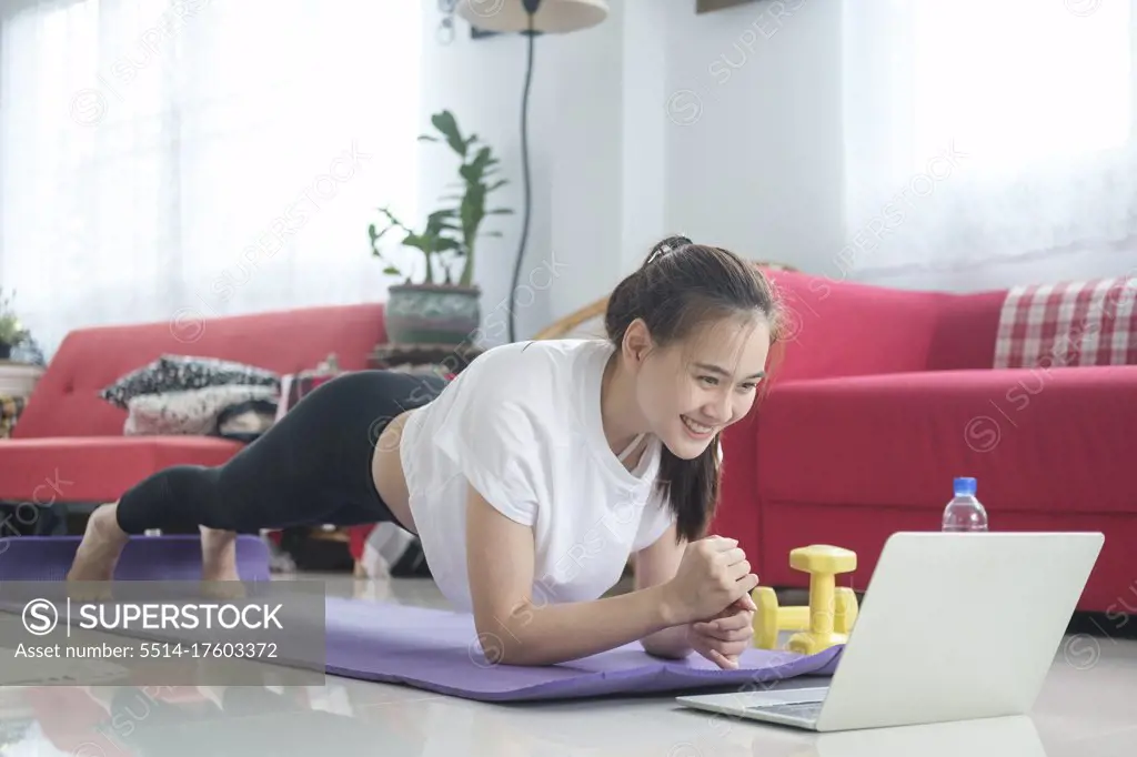 Fit woman doing yoga plank and watching online tutorials.