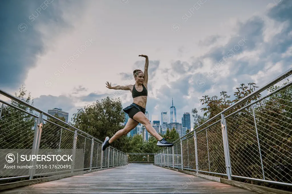 Female athlete dancing by city park during sunset.