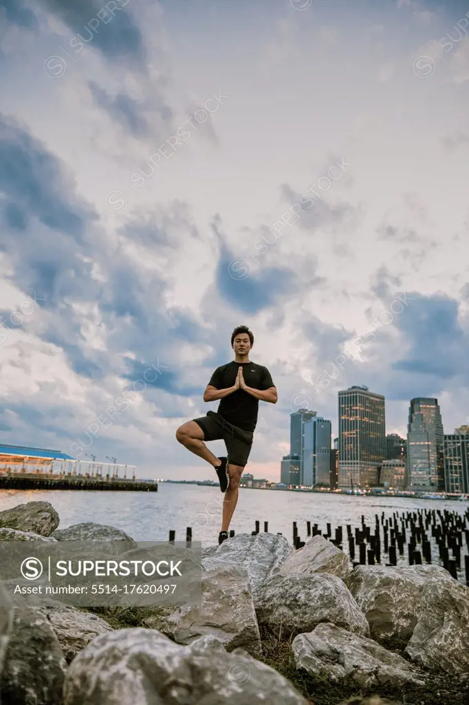 Young athlete meditating during sunset by city skyline.