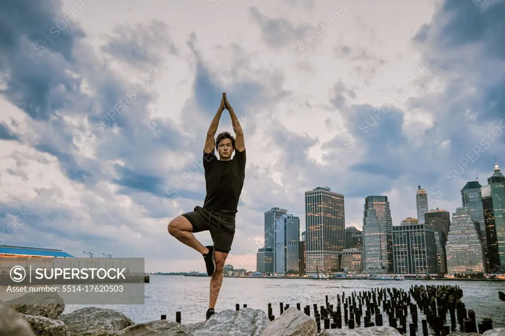 Young athlete meditating during sunset by city skyline.