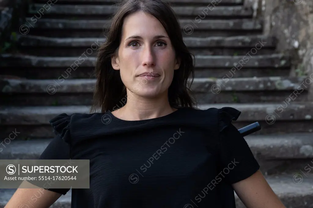 Portrait of young woman in a wheelchair with serious look with some st