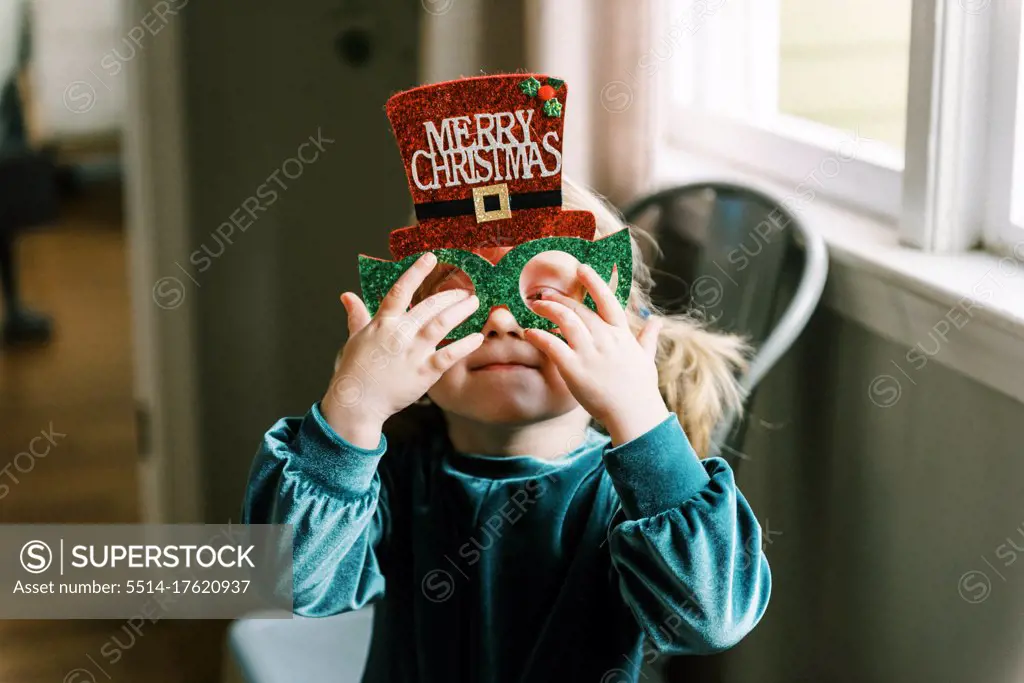 Little happy girl wearing silly Christmas glasses on the holiday