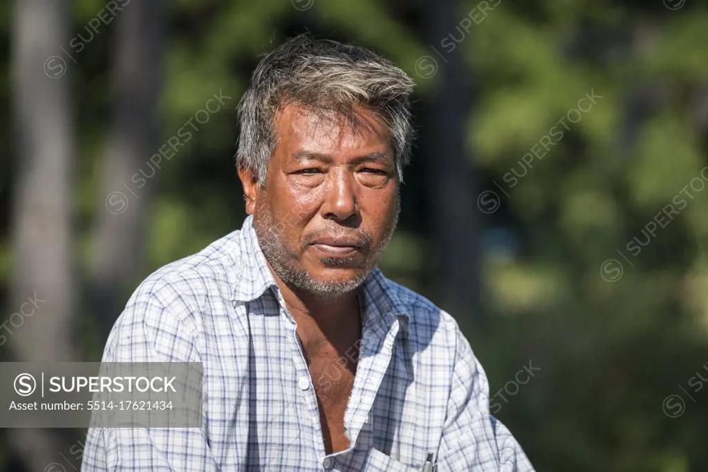 Mature Burmese man looking sitting outdoors, Inwa, Mandalay, Myanmar