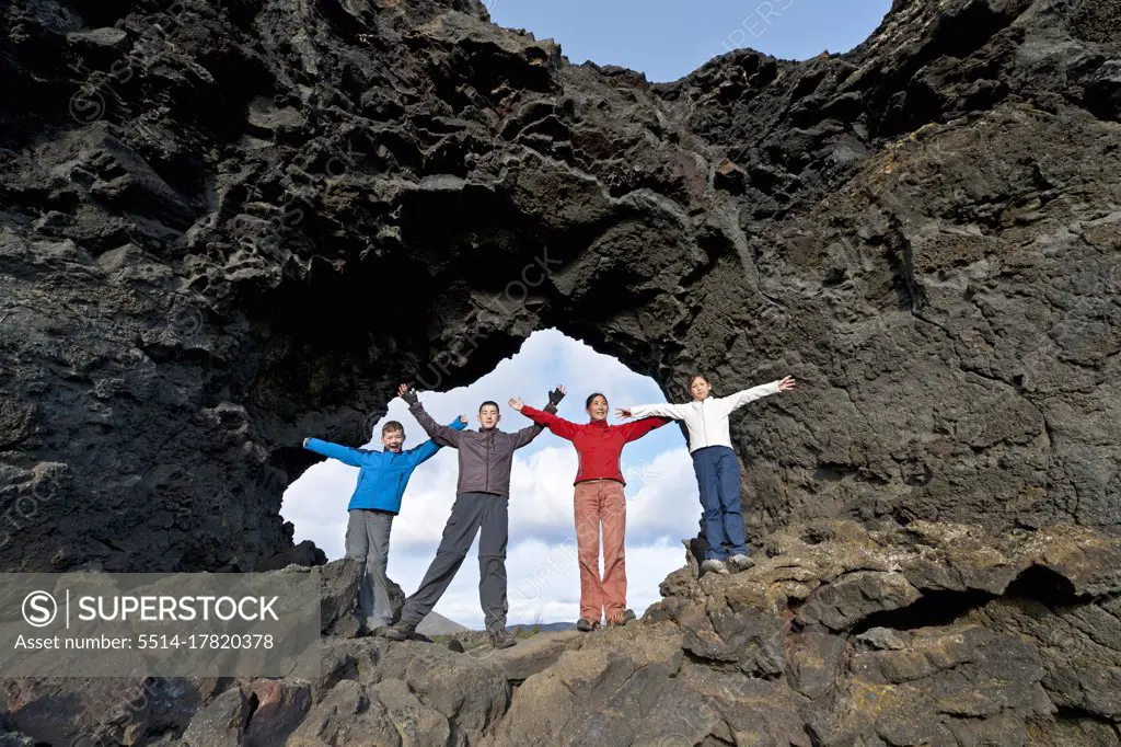 Family is posing at natural stone arch at Lake Myvatn in Iceland