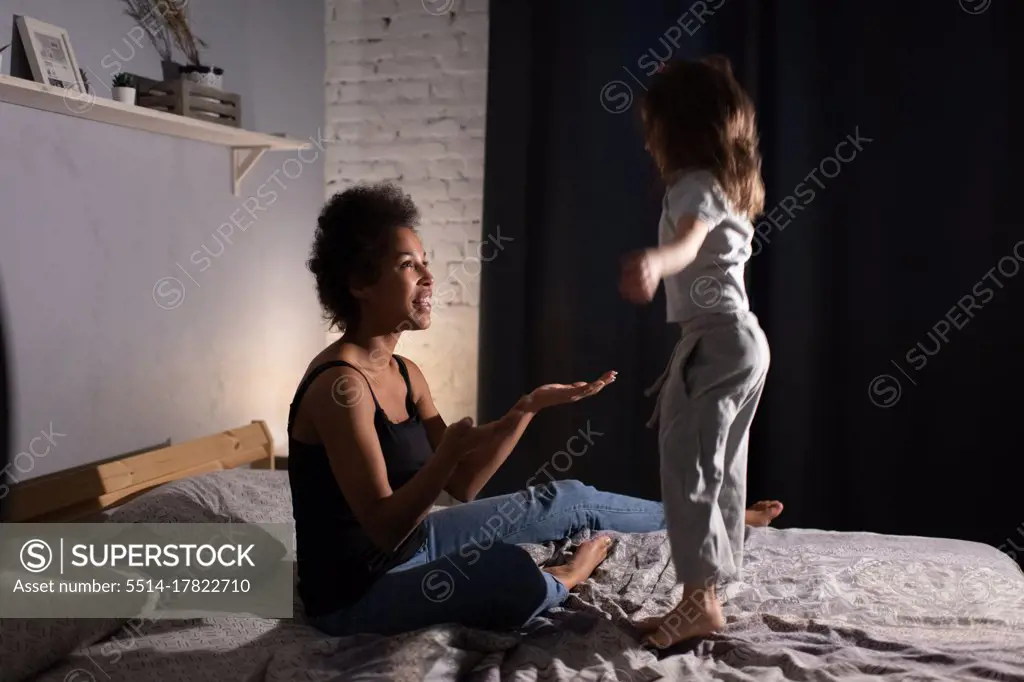 Girl jumping on bed near mother