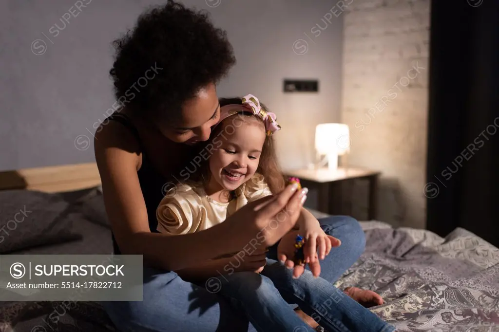Ethnic mother playing with daughter in evening