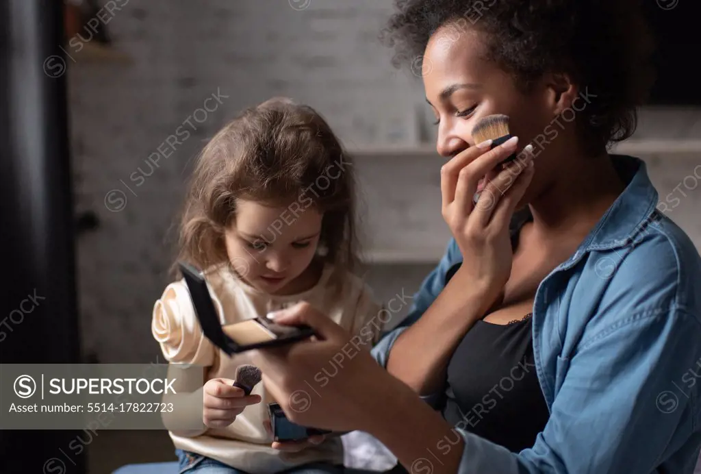 Ethnic woman showing daughter how to apply makeup