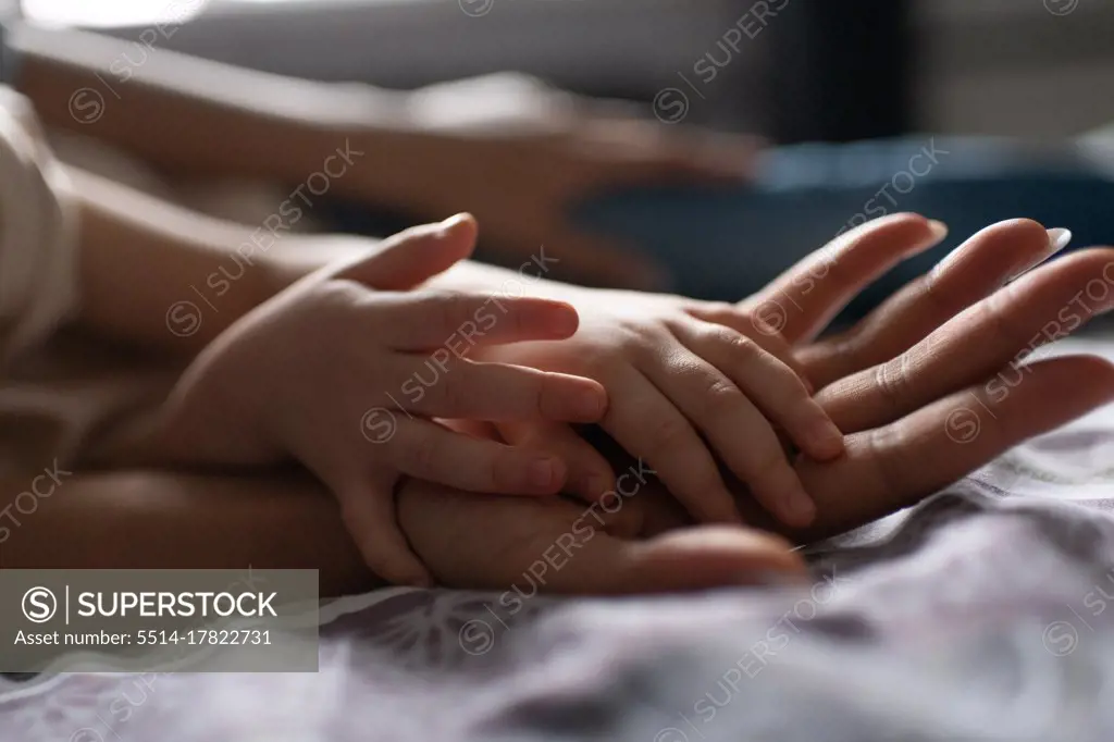 Anonymous mother and child touching hands gently