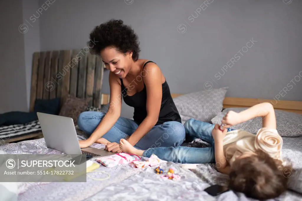 Happy ethnic mother making video call near daughter