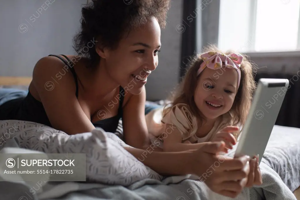 Mixed race other and daughter playing on tablet at home
