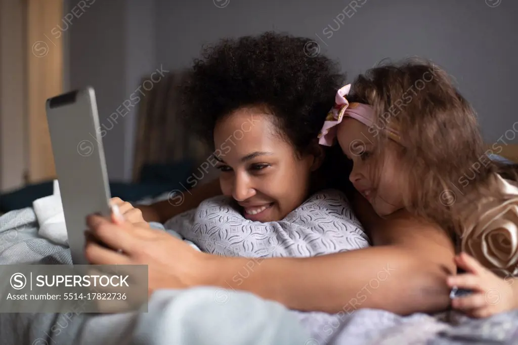 Ethnic mother and daughter having virtual meeting with relatives