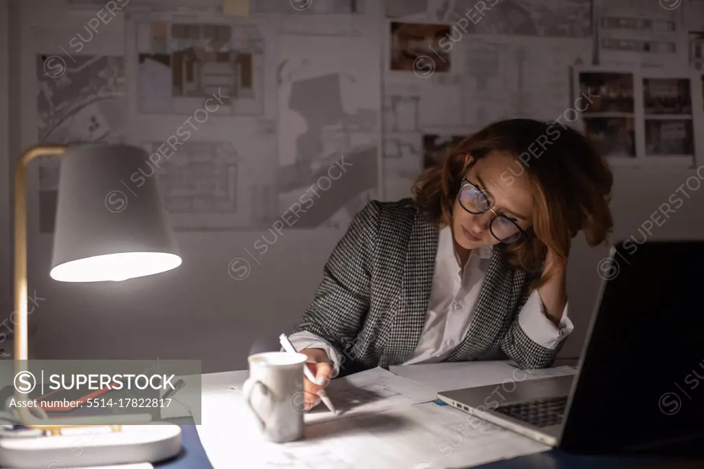 Exhausted businesswoman making notes on draft