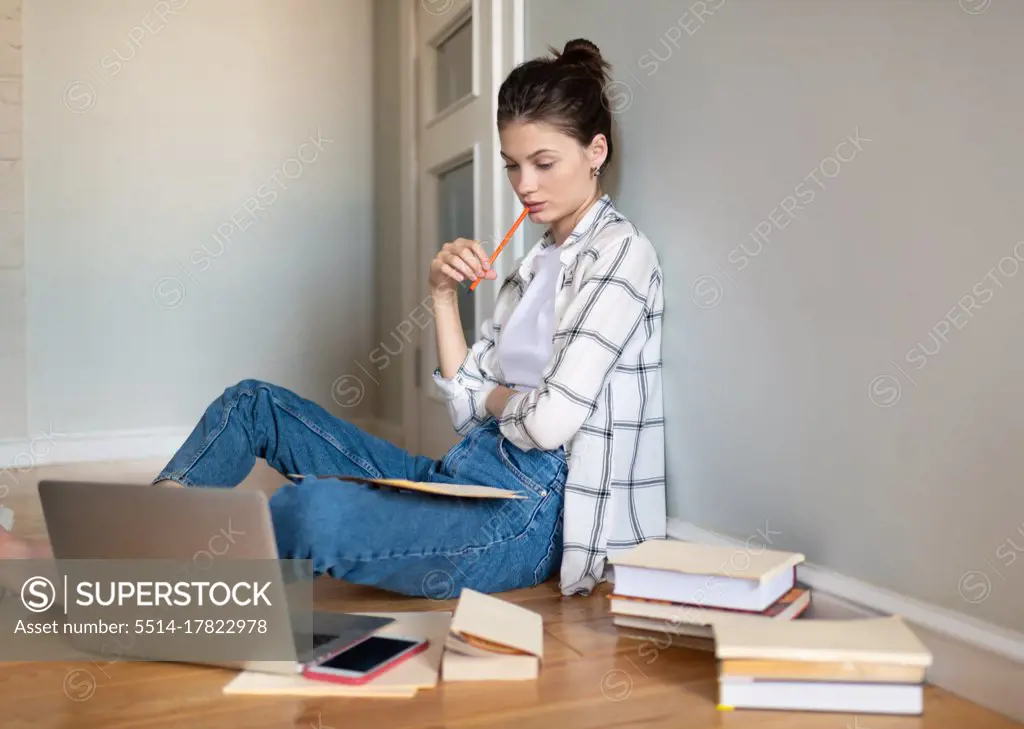 Teenage girl preparing for exam on floor