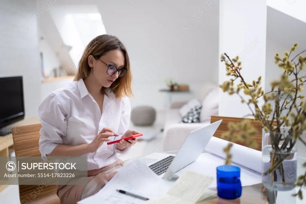Busy woman working at home and using smartphone