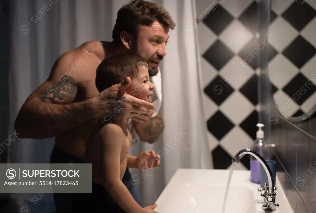 Father and son looking at mirror after shaving
