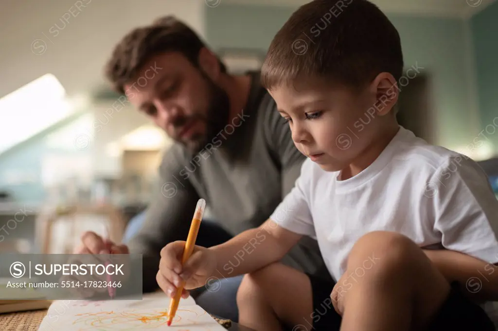Focused boy drawing with father