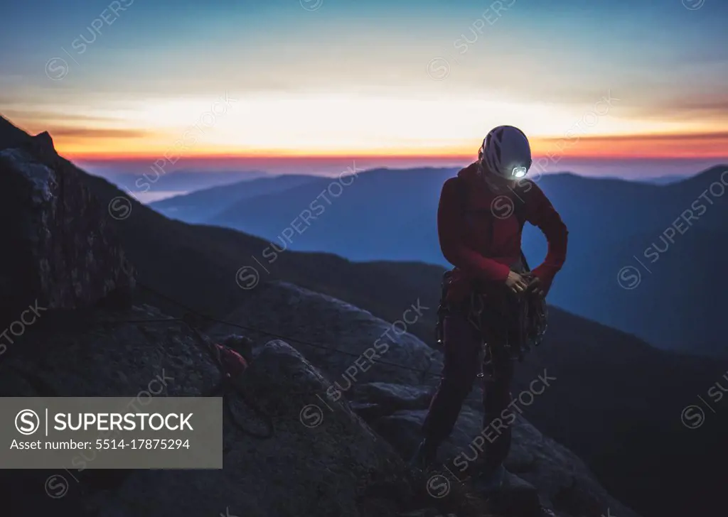 Woman sorting rock gear in the mountains before sunrise