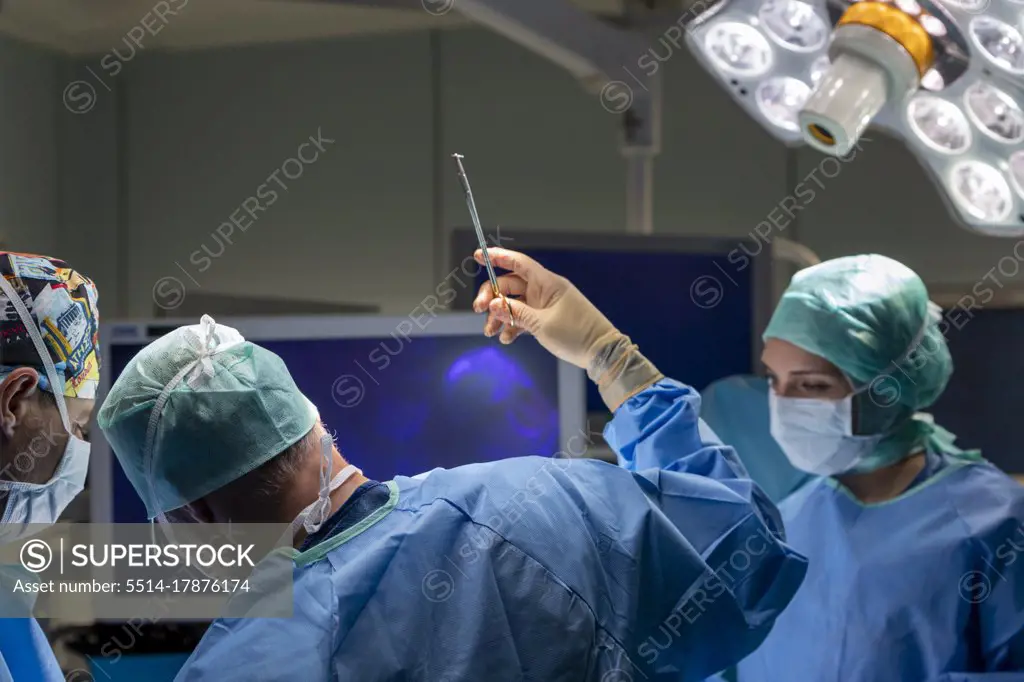 a surgeon sews up a patient in the operating room