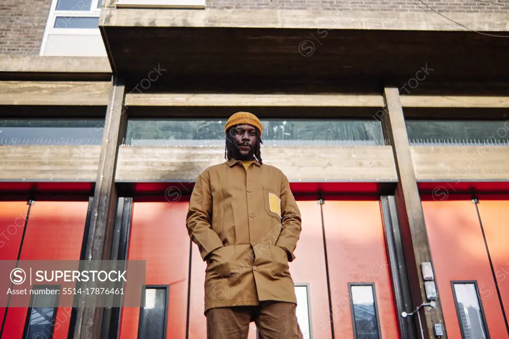 young african guy looking at camera while posing for a photo in front of colorful doors