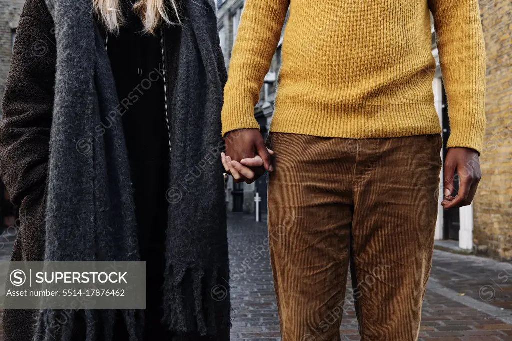 cropped view of biracial couple holding hands. unrecognizable