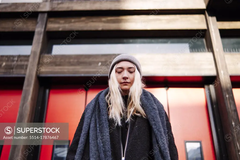 young woman standing in front of building with her eyes closed. low angle shot