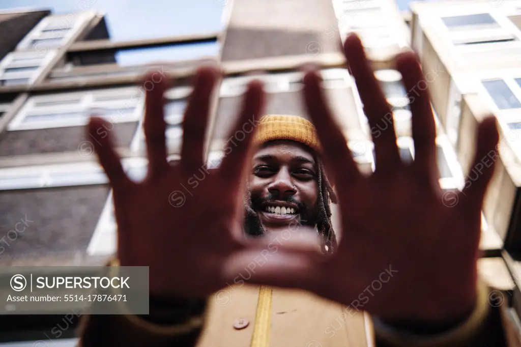 young african guy smiling and gesturing with his hands while looking at camera. low angle shot.