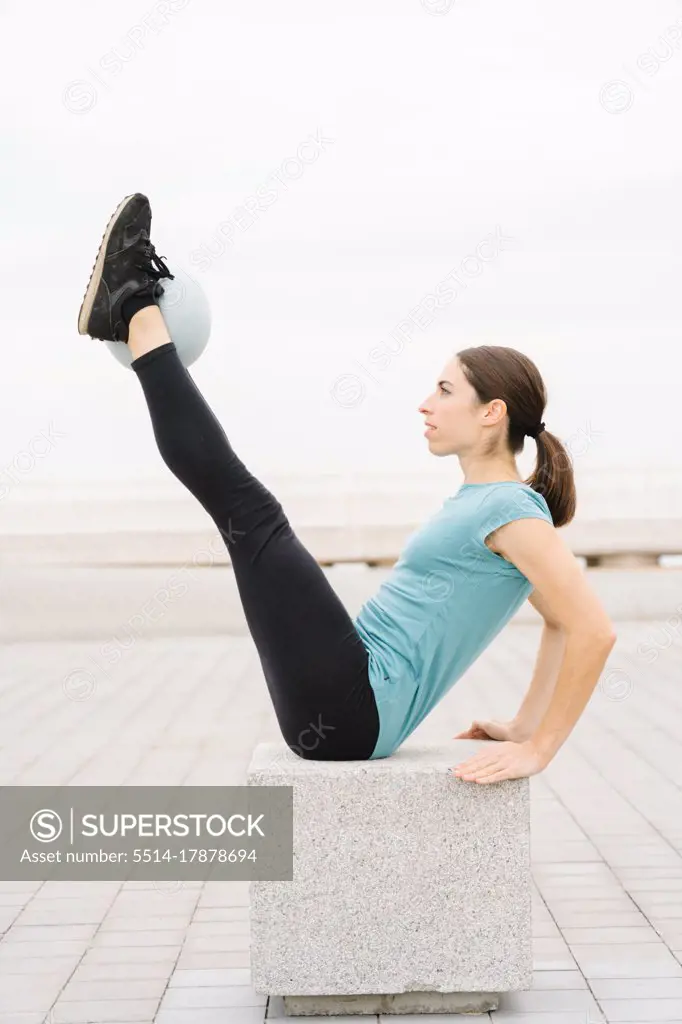 girl doing yoga. practicing the teaser pose with a softball. Pilates