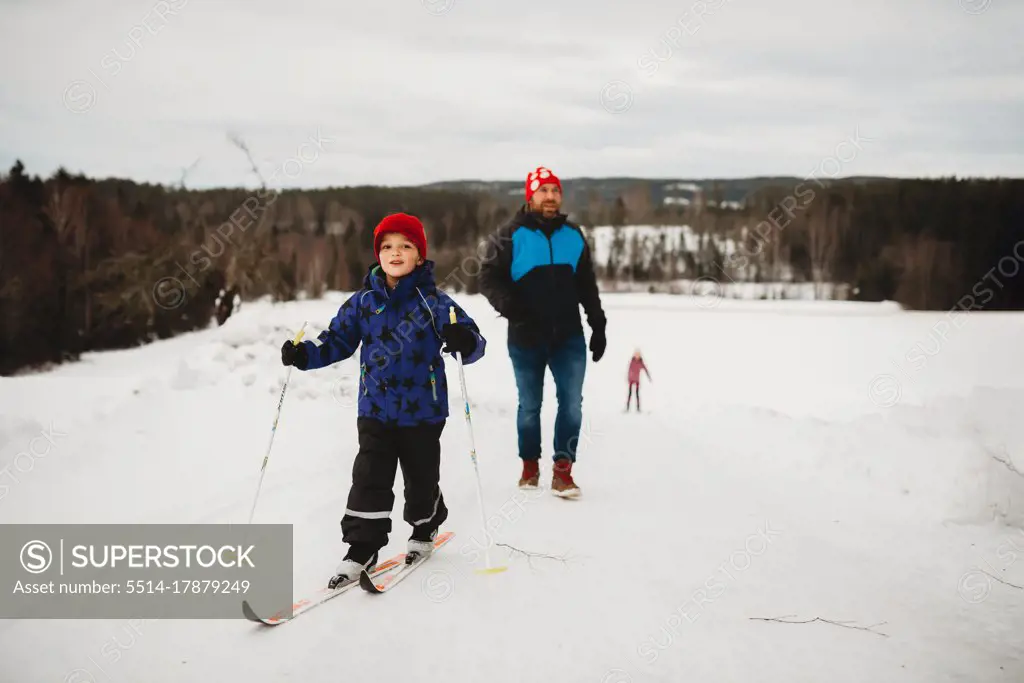 Winter fun boy smiling on skis with family behind him on snowy day