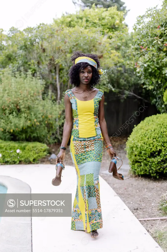 Portrait African wearing traditional dress by pool garden