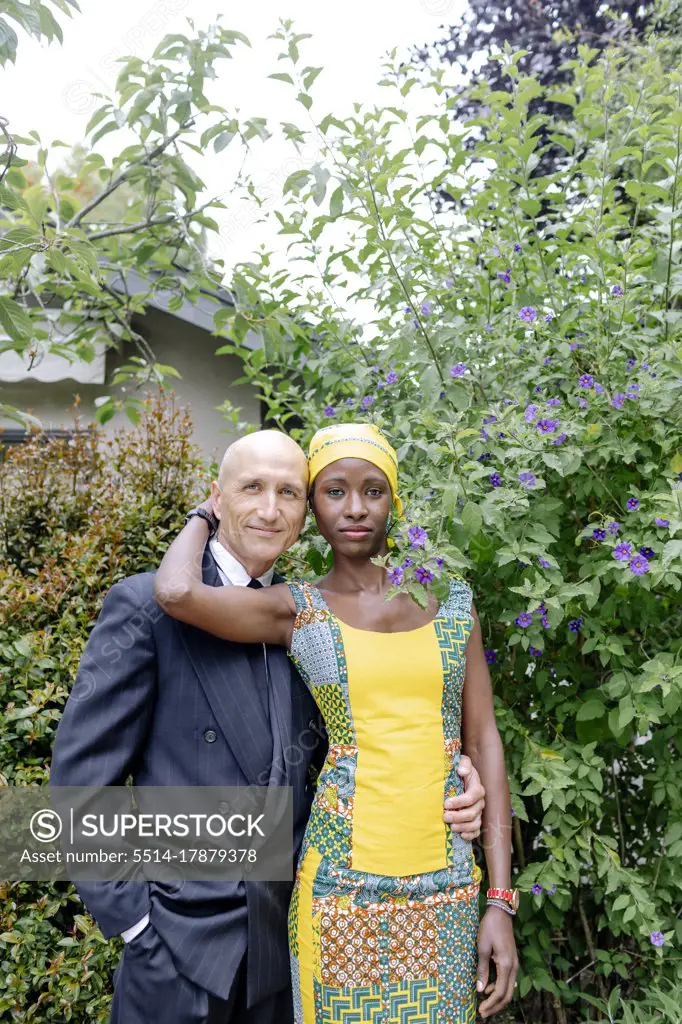 Interracial couple standing up portrait by garden