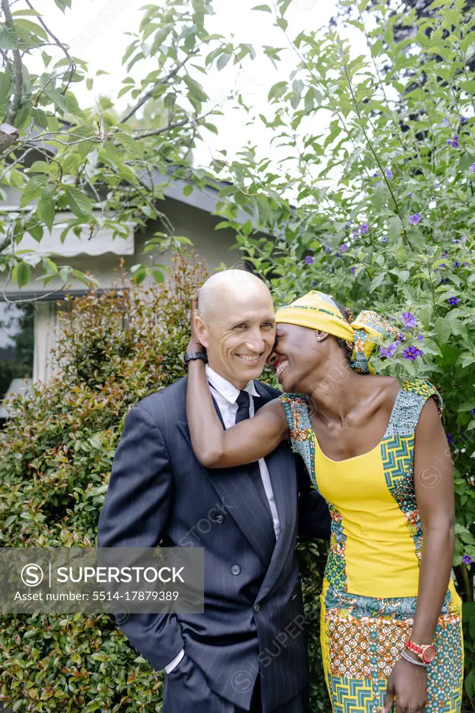 Happy interracial couple hugging and laughing by backyard