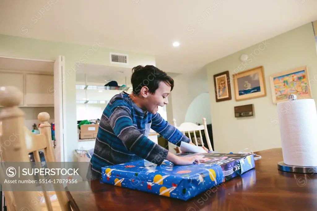 Boy Smiles Excitedly As He Opens Up His Birthday Present