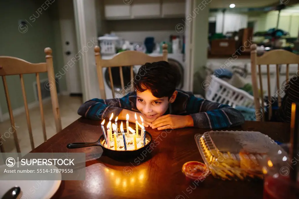 Boy Smiles At The Candles On His Cast Iron Pan Birthday Cake