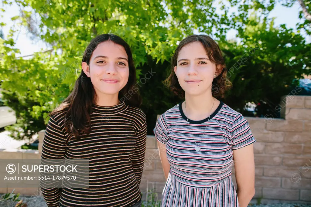 Sisters Wearing Contrasting stripes Offer Polite Smiles To The Camera