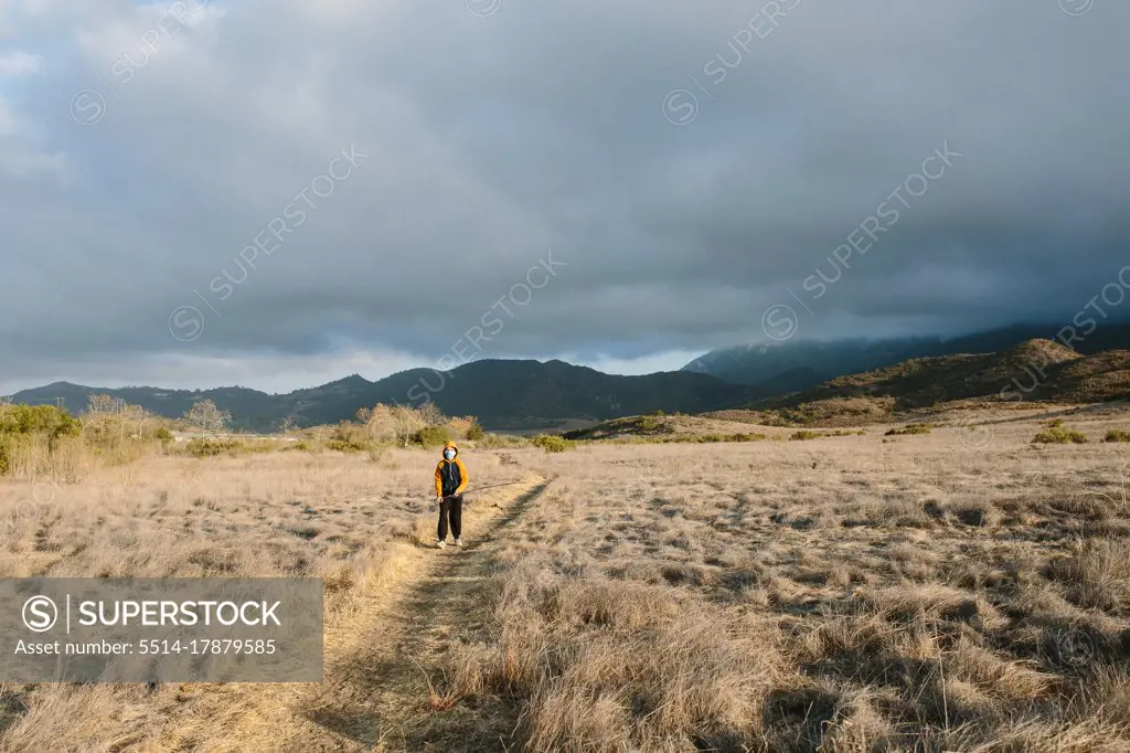 Boy Walks On A Nature Trail In The Sunshine As A Storm Rolls In