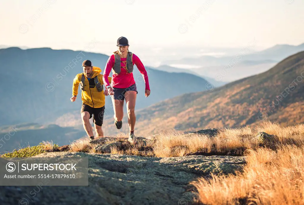 Man and woman trail running in mountains in morning