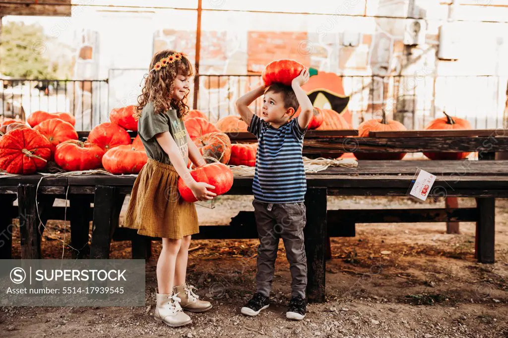 Brother and sister holding cinderella pumpkins at local farmers market