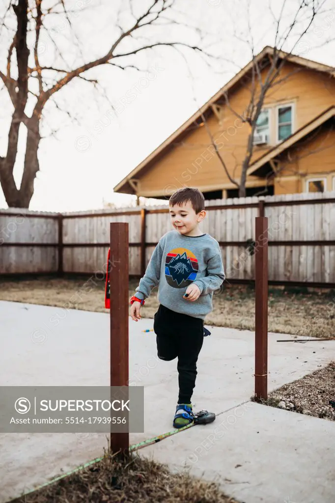 Young boy using level while building fence outside in winter