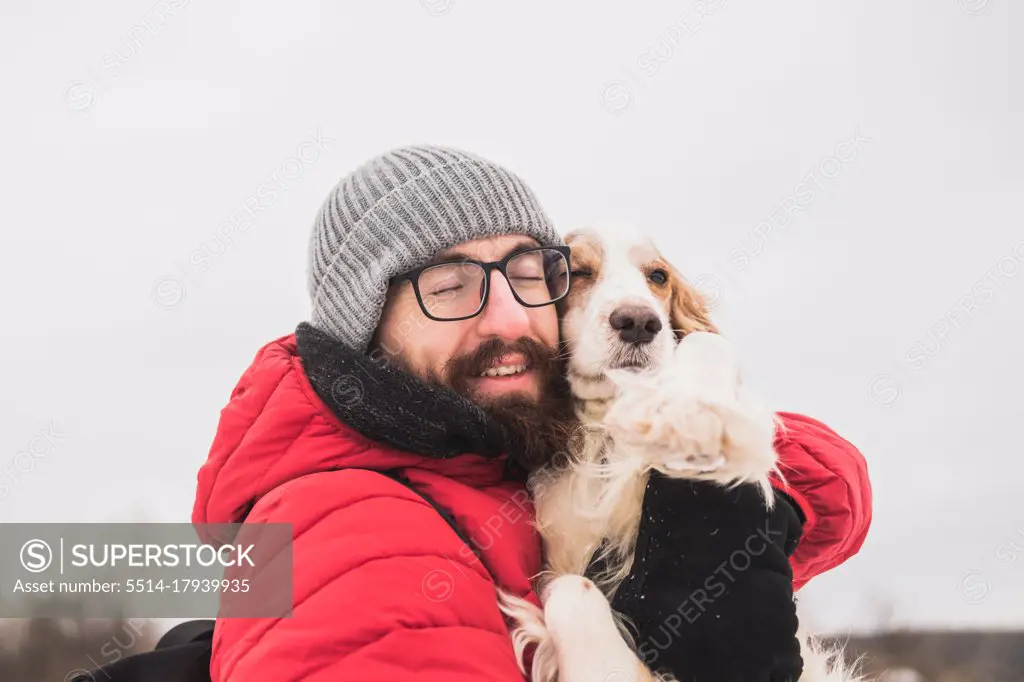 Happy male person hugs his spaniel dog at a walk.