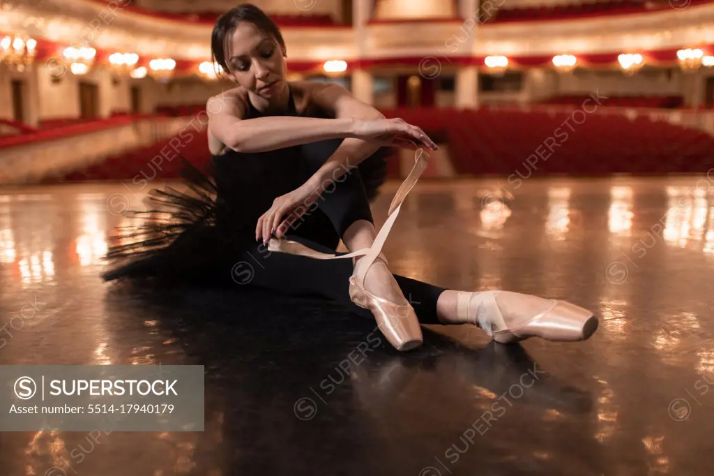 Woman tying ballet slippers on stage