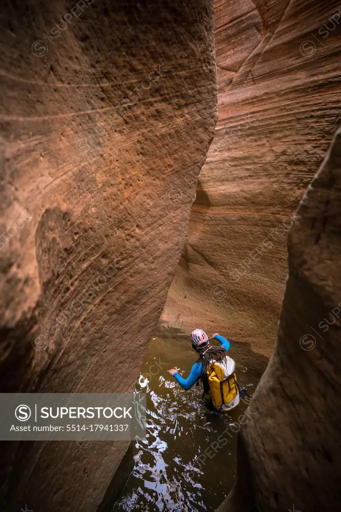 A man wades through deep water to navigate a slot canyon in Zion