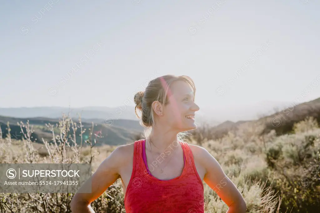 Athletic blonde woman laughs with sun and mountains behind her