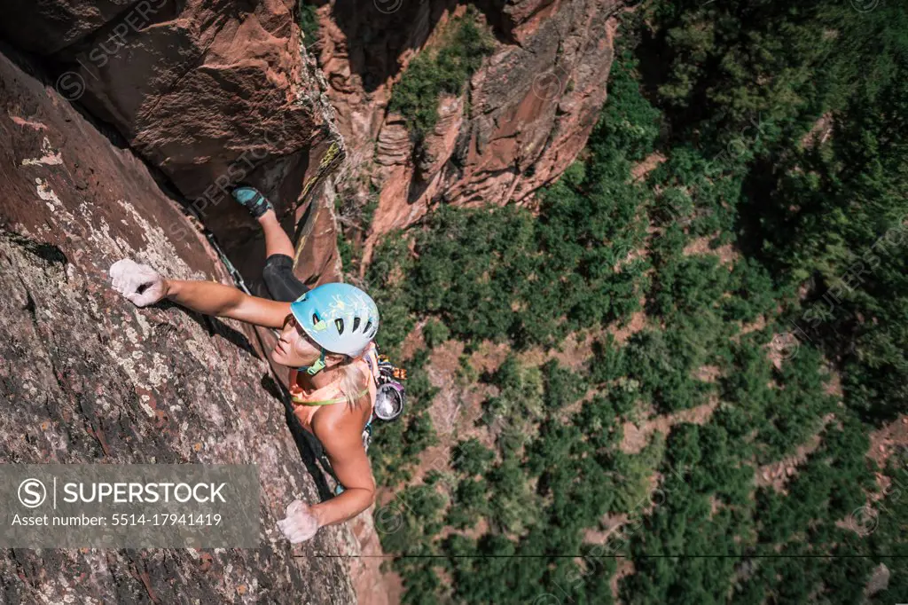Female climber holds crimpers but stays focused high on the wall