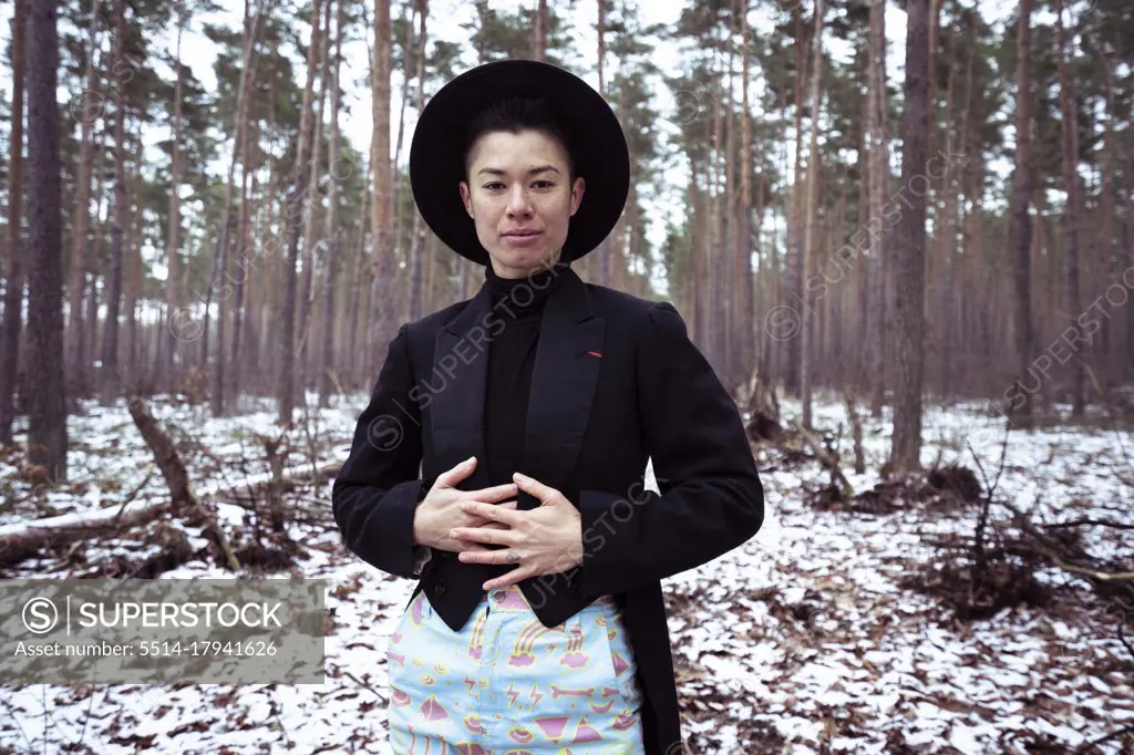 Queer trendy woman stands in white european forrest during winter
